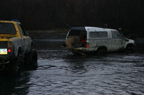2003 Jeep TJ - Two off-road vehicles are partially submerged in shallow, murky water.