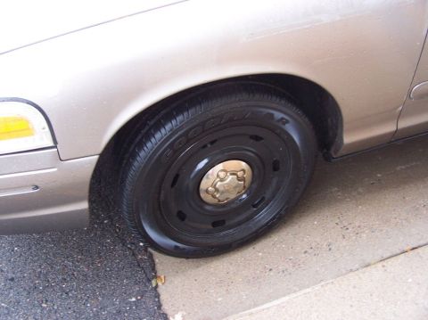 2001 Ford Crown Victoria - Close-up view of the wheel and fender of a tan 2001 Ford Crown Victoria.