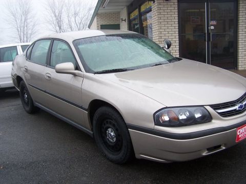 2001 Ford Crown Victoria - A tan sedan is parked outside a business with a red license plate on the front bumper.