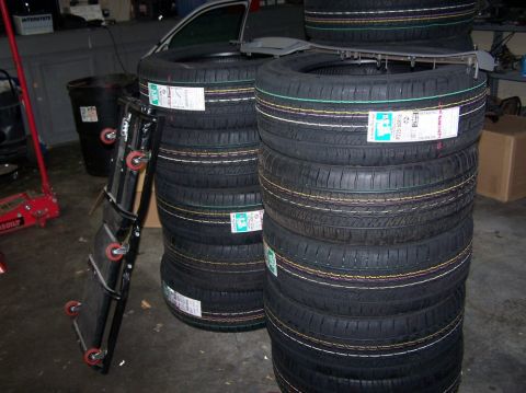 2001 Ford Crown Victoria - Several stacks of new tires are stored indoors, with a red car jack visible to the left.