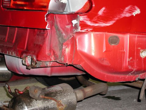 1992 Ford Taurus - Rear view of a damaged red car, showing bent metal and an exhaust pipe.