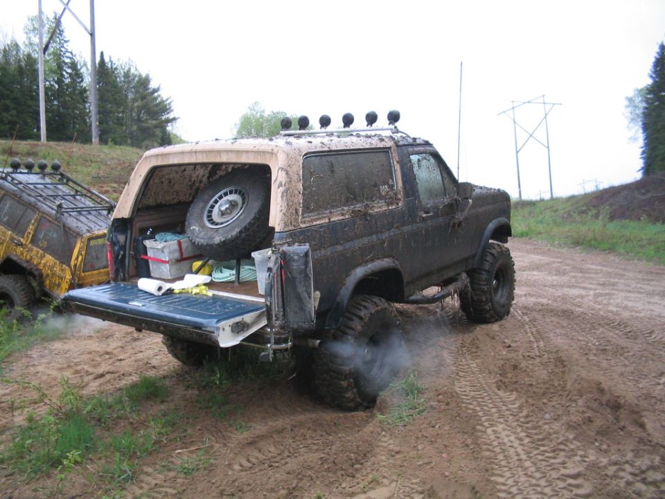 Rear view of muddy 1986 Ford Bronco with tailgate down and spare tire visible in cargo area