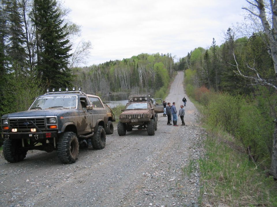 Dark blue 1986 Ford Bronco with off-road modifications on a gravel road