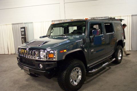 2001 Ford Crown Victoria - Dark green Hummer H2 SUV with a prominent chrome grille and side steps is shown from the front driver's side.