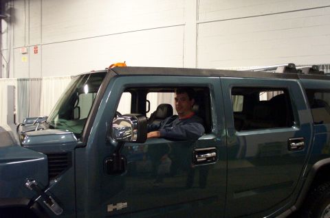 2001 Ford Crown Victoria - A man sits in the driver's seat of a dark green Hummer H2, viewed from the front passenger side.