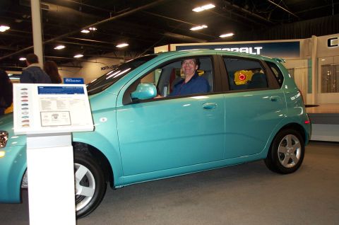 2001 Ford Crown Victoria - A teal hatchback is parked indoors with a person in the driver's seat and a window sticker on display.