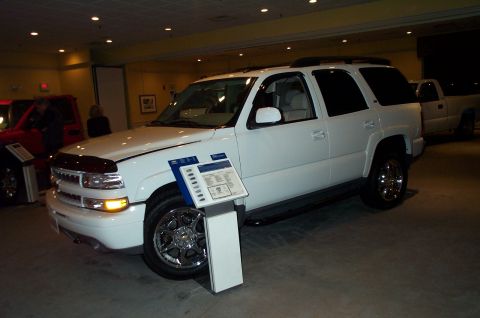 2001 Ford Crown Victoria - A white SUV is displayed indoors next to a red vehicle and a pickup truck.