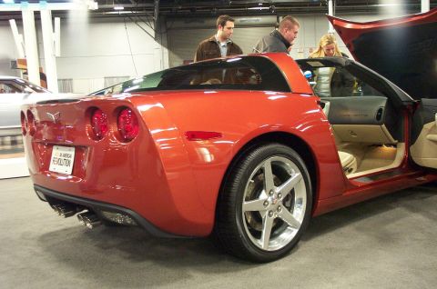 2001 Ford Crown Victoria - A red Chevrolet Corvette C6 is displayed with its door and hood open, attracting attention from onlookers.