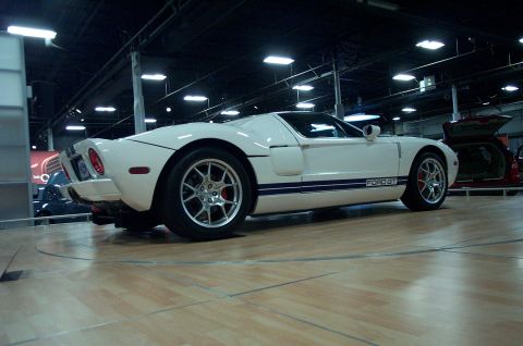 2001 Ford Crown Victoria - A white Ford GT with blue racing stripes is displayed indoors on a rotating platform.