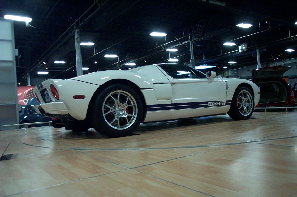 White Ford GT with blue racing stripes, silver wheels, and red brake calipers
