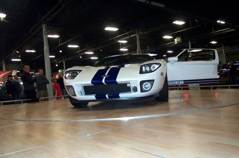 2001 Ford Crown Victoria - White 2005 Ford GT sports car with blue racing stripes, driver's door ajar.