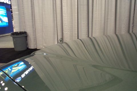 2001 Ford Crown Victoria - Reflection of a Subaru display on the hood of a car.