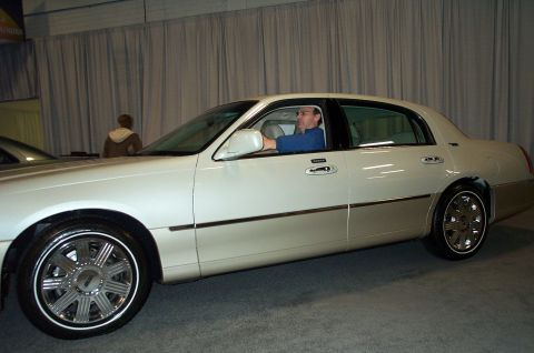 2001 Ford Crown Victoria - Man driving a white Lincoln Town Car with a two-tone paint scheme and chrome wheels.