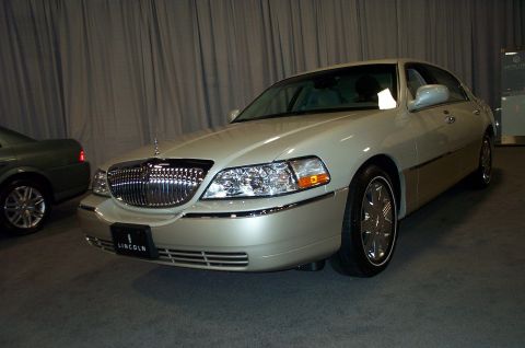 2001 Ford Crown Victoria - A Lincoln Town Car is displayed indoors with a curtain backdrop and another vehicle nearby.