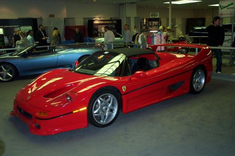 2001 Ford Crown Victoria - A red Ferrari F50 is displayed alongside a blue convertible and other items at an indoor event.