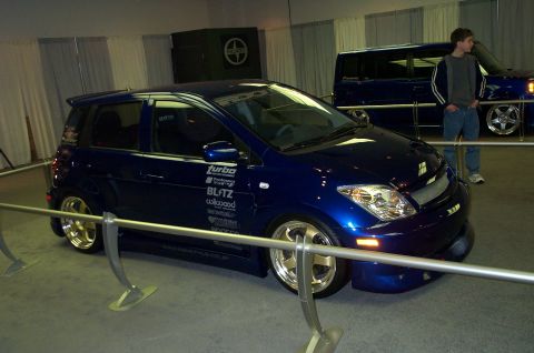 2001 Ford Crown Victoria - A custom blue hatchback with gold rims and various racing decals is displayed at an event.