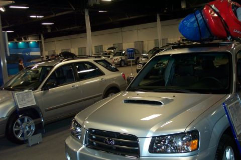 2001 Ford Crown Victoria - Silver Subaru Forester on display with kayaks secured to its roof rack, parked indoors at an auto show.