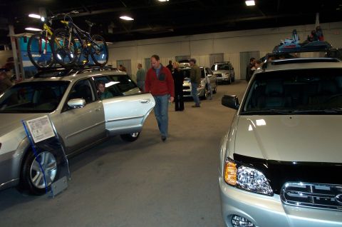 2001 Ford Crown Victoria - Two silver Subaru wagons are displayed indoors, one with bikes on its roof rack.