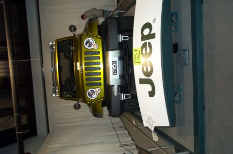 2001 Ford Crown Victoria - A yellow Jeep Wrangler is displayed indoors next to a large Jeep logo sign.
