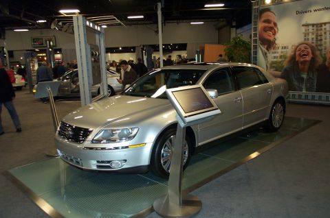 2001 Ford Crown Victoria - A silver sedan is displayed at an auto show with a promotional banner in the background.