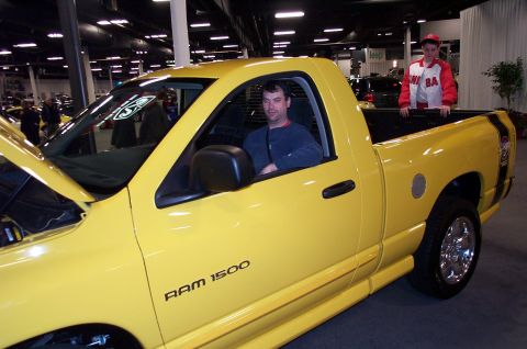 2001 Ford Crown Victoria - Yellow Dodge Ram 1500 pickup truck with two people visible inside and in the bed.