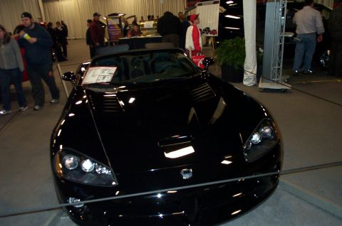 2001 Ford Crown Victoria - A black convertible sports car is displayed indoors, with people in the background.