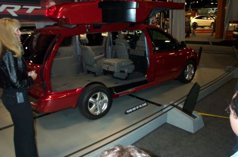 2001 Ford Crown Victoria - Red minivan interior displayed with seats removed and doors open at an exhibition.