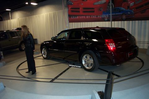 2001 Ford Crown Victoria - A black station wagon is displayed on a rotating platform in front of a banner.
