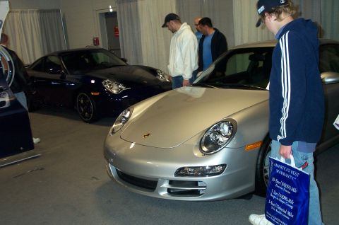 2001 Ford Crown Victoria - Two Porsche 911 models are displayed indoors with attendees examining them.