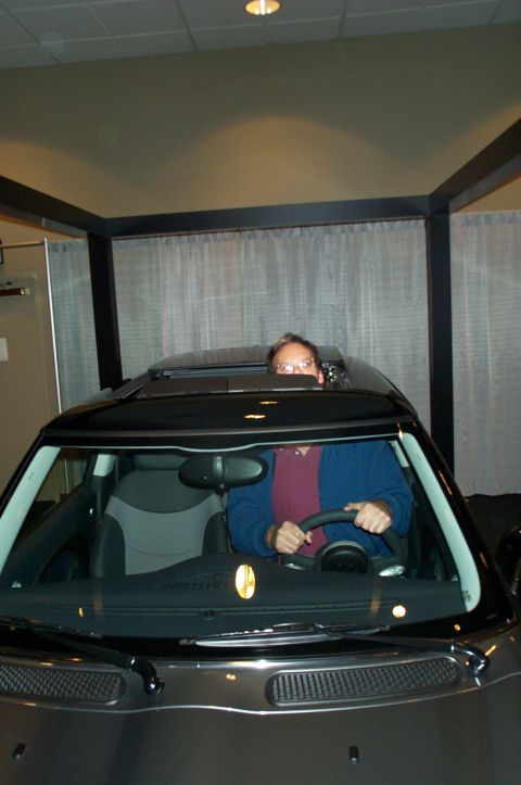 2001 Ford Crown Victoria - A person is seen driving a dark Mini Cooper, with the sunroof open, from a front-facing perspective.