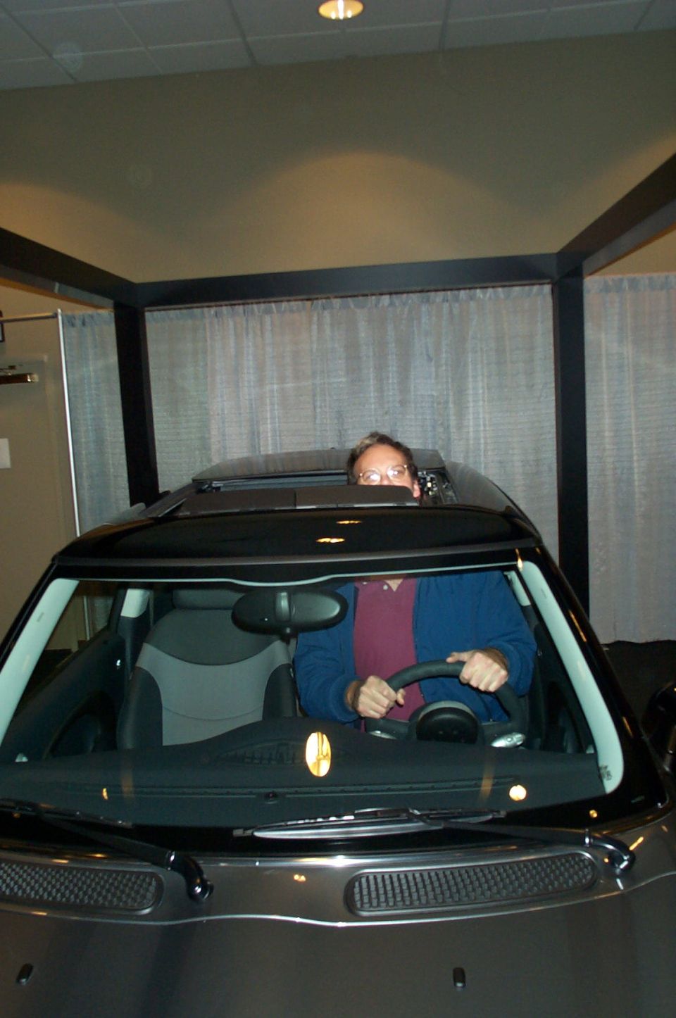 Person driving a dark Mini Cooper with sunroof open