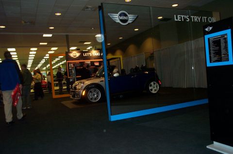2001 Ford Crown Victoria - A blue Mini Cooper convertible is displayed indoors with signage and people nearby.