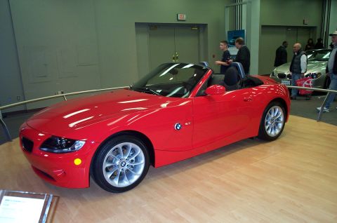 2001 Ford Crown Victoria - A red convertible is displayed indoors on a wooden floor with other vehicles in the background.