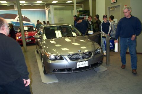 2001 Ford Crown Victoria - A silver BMW sedan, identified by its S45i badge, is displayed indoors with other vehicles and potential buyers.