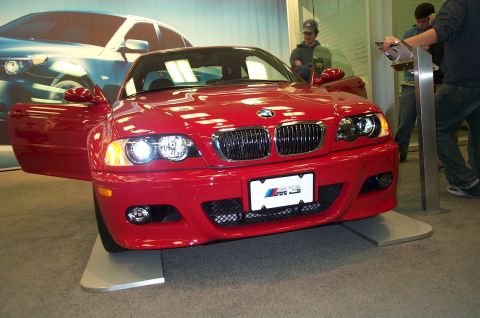 2001 Ford Crown Victoria - A red BMW M3 is displayed with its door open, showing the interior and front grille.