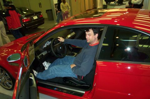 2001 Ford Crown Victoria - Man sits in a red BMW M3 coupe, with another black BMW in the background.