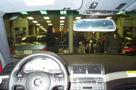 2001 Ford Crown Victoria - View from inside a BMW 545i, showing the dashboard and other vehicles in a dealership showroom.