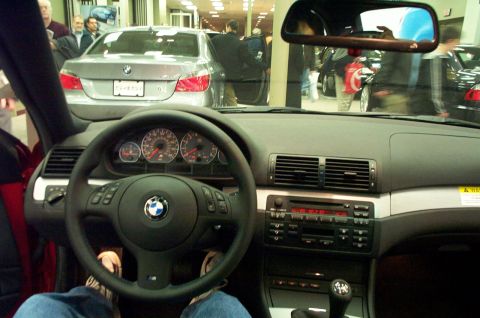 2001 Ford Crown Victoria - Interior view of a BMW, the dashboard, steering wheel, and center console. Another BMW is visible through the windshield.