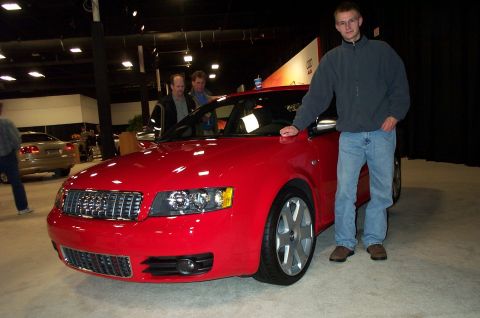 2001 Ford Crown Victoria - A man poses with a red Audi S4 at an indoor car show. Another vehicle is visible in the background.