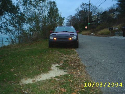 1997 Ford Taurus - Car parked on the side of the road with a car bra and illuminated parking lights.