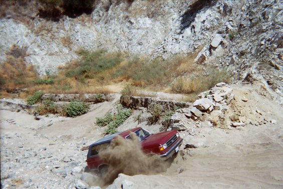 1989 Ford Bronco driving through dust off-road
