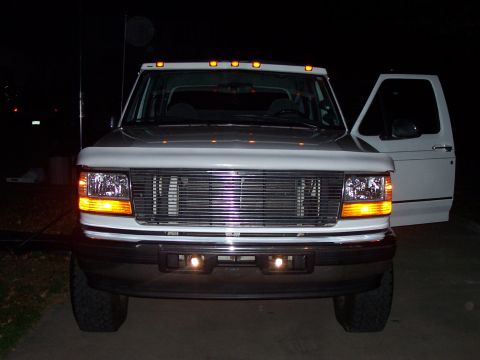 1994 Ford Bronco - Front view of a white Ford F-Series truck with its driver's door open at night.