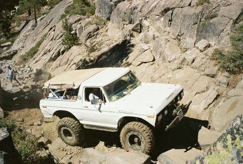 1994 Ford Bronco - A white 1978 Ford Bronco navigates a challenging rocky terrain on an off-road trail.