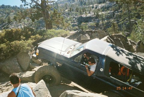 1994 Ford Bronco - A Ford Bronco tackles a challenging off-road course with large rocks and steep terrain.