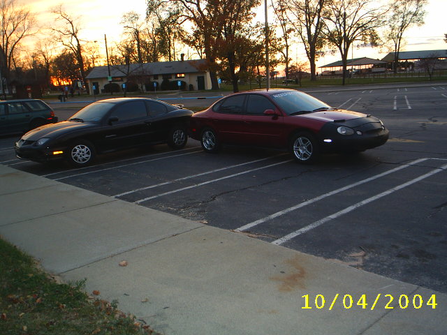 Red 1997 Ford Taurus with a black car next to it in a parking lot