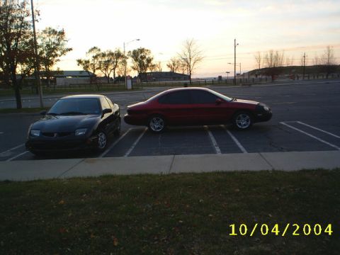 1997 Ford Taurus - Two sedans are parked side-by-side in an outdoor lot during the golden hour.