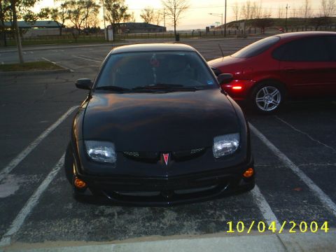 1997 Ford Taurus - A black Pontiac Sunfire is parked in a lot with a red car behind it.