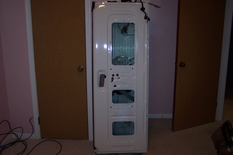 White-painted truck tailgate shell standing indoors with access holes exposed