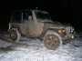 2003 Jeep TJ - A muddy 2003 Jeep TJ is parked in a snowy area at night.