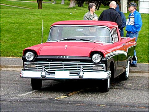 1967 Ford Ranchero - A two-tone red and black Ford pickup truck is parked on asphalt with people standing nearby.